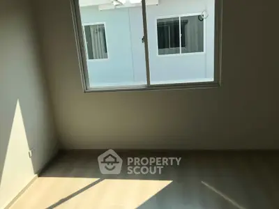 Bright empty room with large window and wooden flooring, perfect for customization.