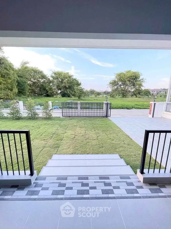 Charming garden view from a modern patio with lush greenery and open space.