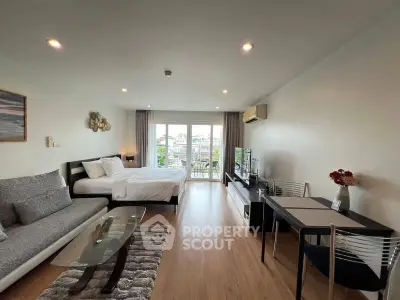 Spacious modern studio apartment with large windows and stylish furnishings.