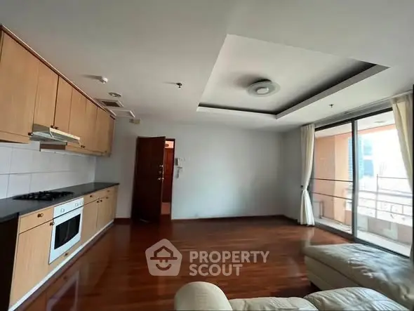 Spacious living room with open kitchen and balcony access in modern apartment.