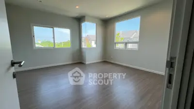 Spacious empty room with large windows and wooden flooring, perfect for customization.