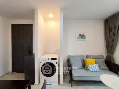 Modern apartment interior with washing machine and cozy seating area.