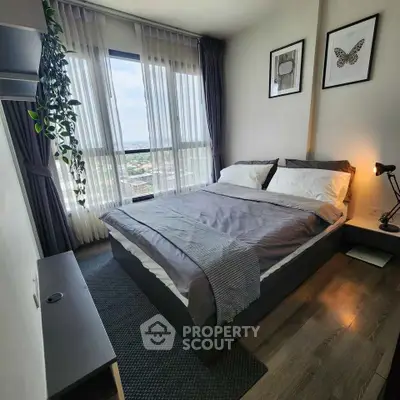 Modern bedroom with large window and stylish decor in a high-rise apartment.