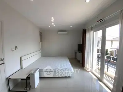 Spacious bedroom with large windows and balcony access, featuring modern minimalist design.