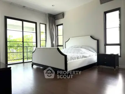Spacious bedroom with elegant bed and large windows overlooking greenery.