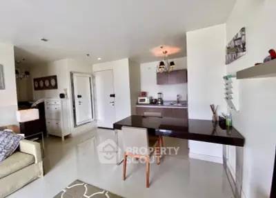 Modern open-plan living room with sleek kitchen and dining area, featuring contemporary furniture and decor.