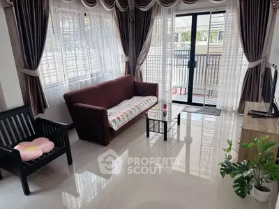 Bright living room with modern furniture and large windows leading to a balcony.