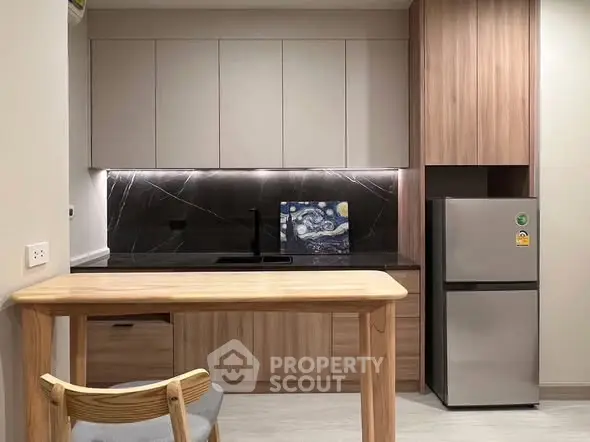 Modern kitchen with sleek cabinetry and stainless steel fridge in a stylish apartment.