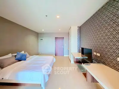 Spacious modern bedroom with stylish decor and flat-screen TV, perfect for relaxation and comfort.