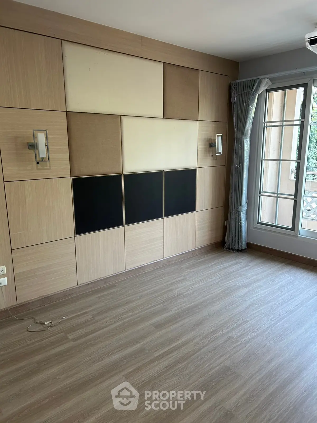 Spacious empty room with modern wood paneling and large window for natural light