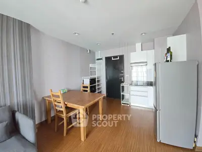 Modern kitchen with wooden dining table and sleek appliances in a cozy apartment setting.