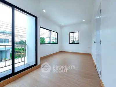 Bright and spacious room with large windows and wooden flooring, perfect for modern living.
