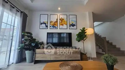 Modern living room with stylish decor and large TV, featuring elegant artwork and natural light.