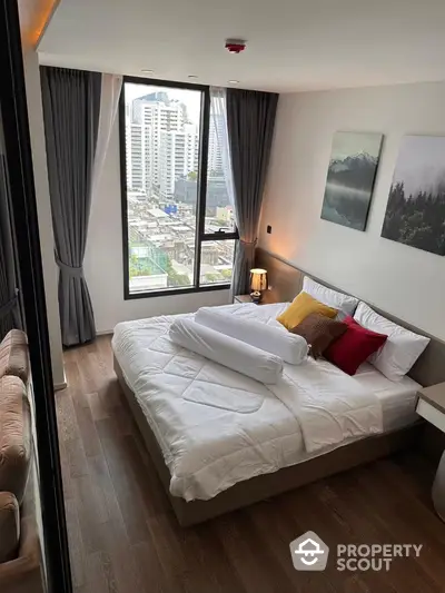 Modern bedroom with city view, featuring stylish decor and large windows for natural light.