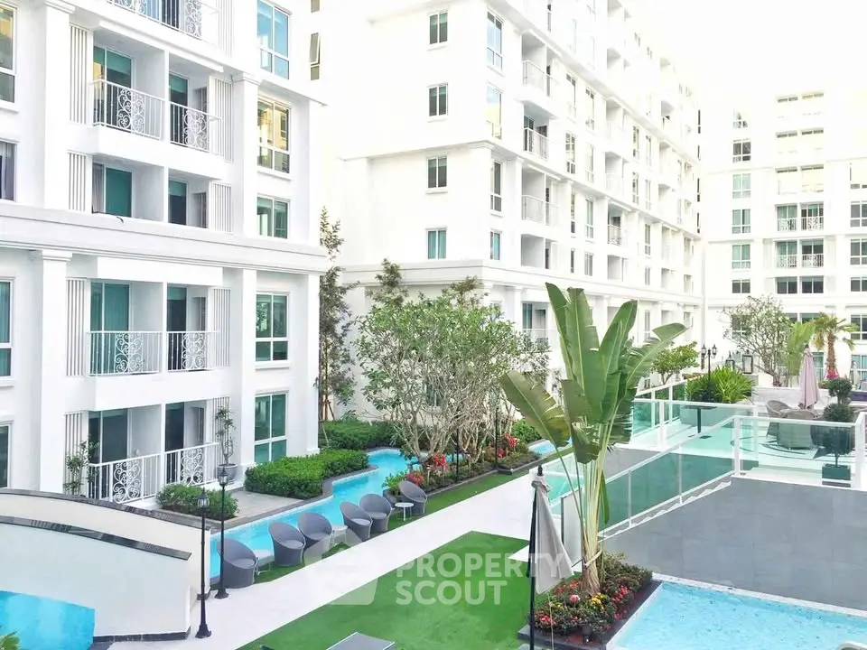 Luxurious modern apartment complex with pool and lush garden view.
