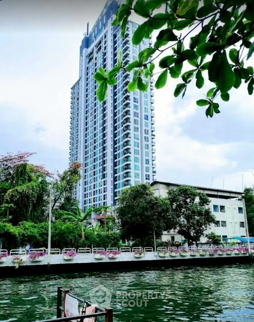 Stunning high-rise building with lush greenery and serene waterway view.