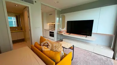 Modern living room with sleek TV setup and cozy yellow sofa in stylish apartment.