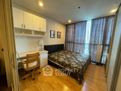 Cozy bedroom with wooden flooring, large window, and built-in desk in modern apartment.