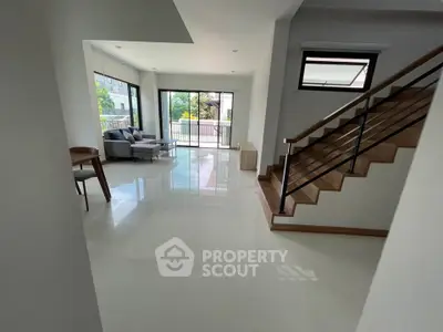 Spacious modern living room with large windows and elegant staircase