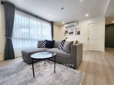 Modern living room with stylish sofa and large window, perfect for relaxation and comfort.