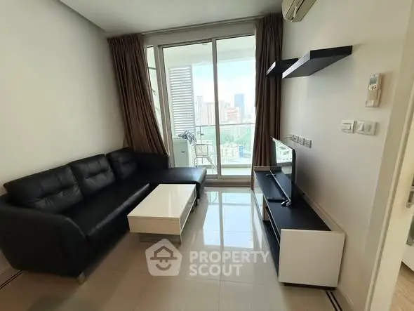 Modern living room with sleek black sofa and city view balcony.