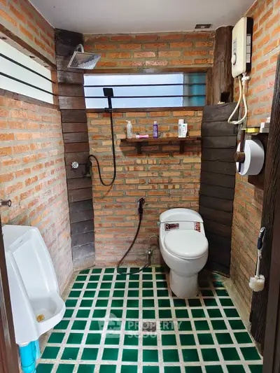 Rustic bathroom with brick walls and modern fixtures, featuring a unique green tiled floor.