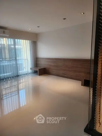 Spacious modern living room with sleek flooring and large windows for natural light.