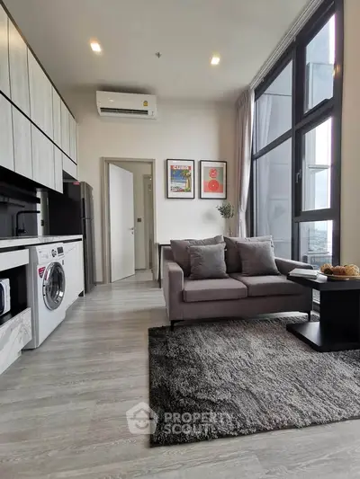 Modern living room with washing machine and large windows in a stylish apartment.