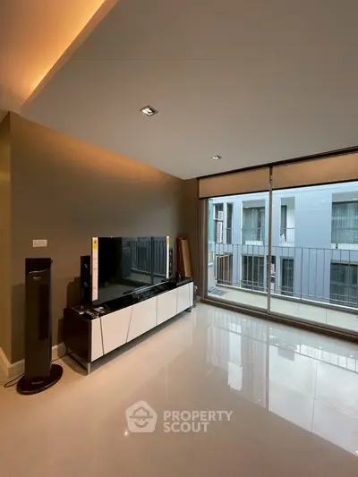 Spacious modern living room with large windows and sleek entertainment unit.