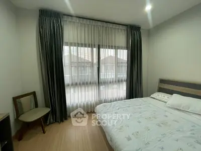 Cozy bedroom with large window and elegant curtains in modern apartment