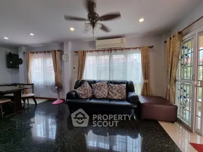 Spacious living room with elegant decor and natural light, featuring a comfortable sofa and ceiling fan.