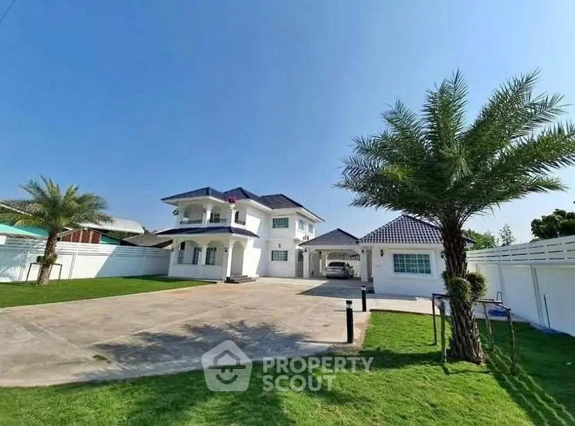 Spacious two-story house with large driveway and lush green lawn under clear blue sky.