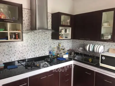 Modern kitchen with dark wood cabinets, gas stove, and sleek backsplash tiles.