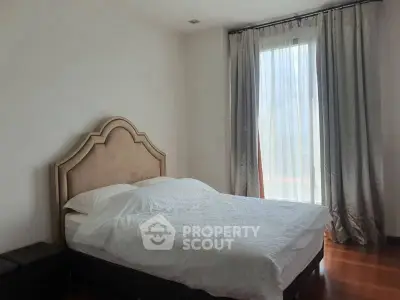 Cozy bedroom with elegant headboard and natural light through sheer curtains.