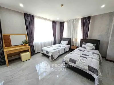 Spacious bedroom with twin beds and elegant decor, featuring large windows and a stylish vanity.