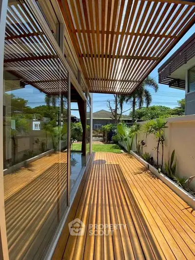 Stunning wooden deck with pergola offering serene garden views in modern home.