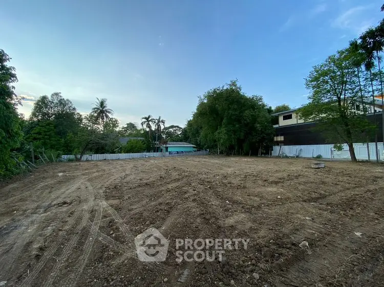 Expansive vacant land plot surrounded by lush greenery, ideal for development opportunities.