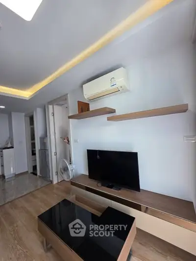 Modern living room with sleek TV setup and air conditioning, featuring wooden flooring and stylish shelves.