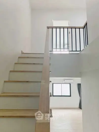 Modern minimalist staircase with wooden railing in bright interior space