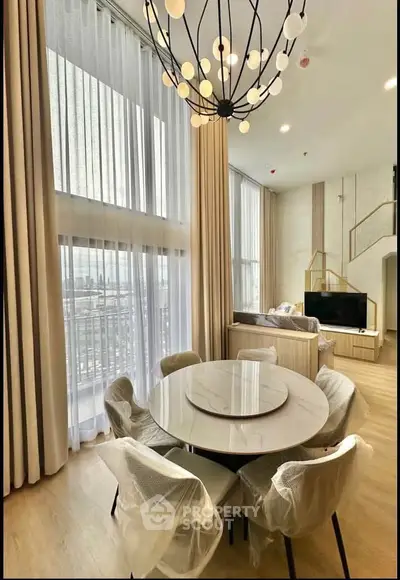 Luxurious high-ceiling living room with modern chandelier and city view