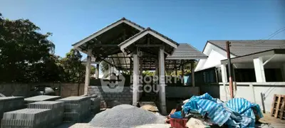 Under-construction house with modern roof design and building materials on site.