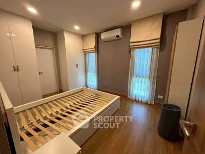 Spacious bedroom with modern design, featuring wooden flooring and ample natural light.