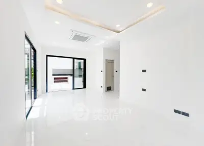 Spacious modern living room with sleek white flooring and large windows for natural light.
