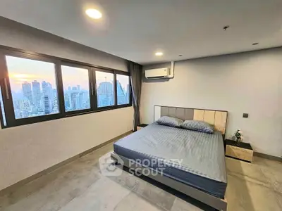 Modern bedroom with city view and large windows in high-rise apartment