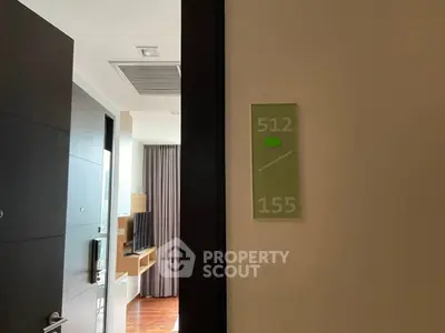 Modern apartment entrance with view into a stylish living room featuring a wall-mounted TV.