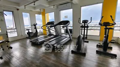 Modern gym with city view featuring treadmills and exercise bikes.