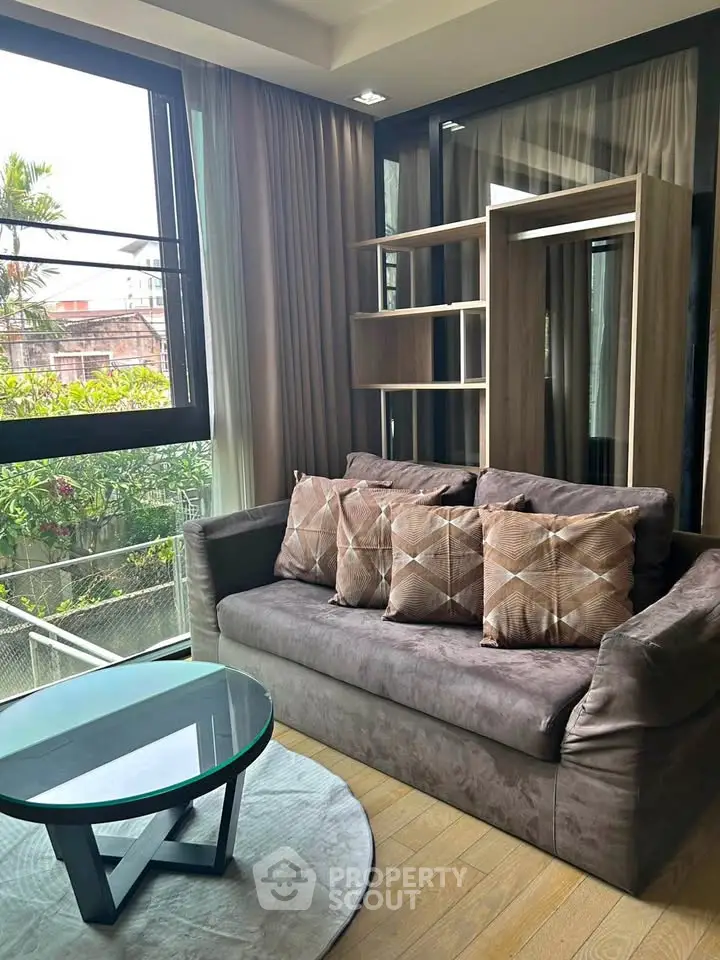 Stylish living room with modern sofa and large window offering lush garden view.