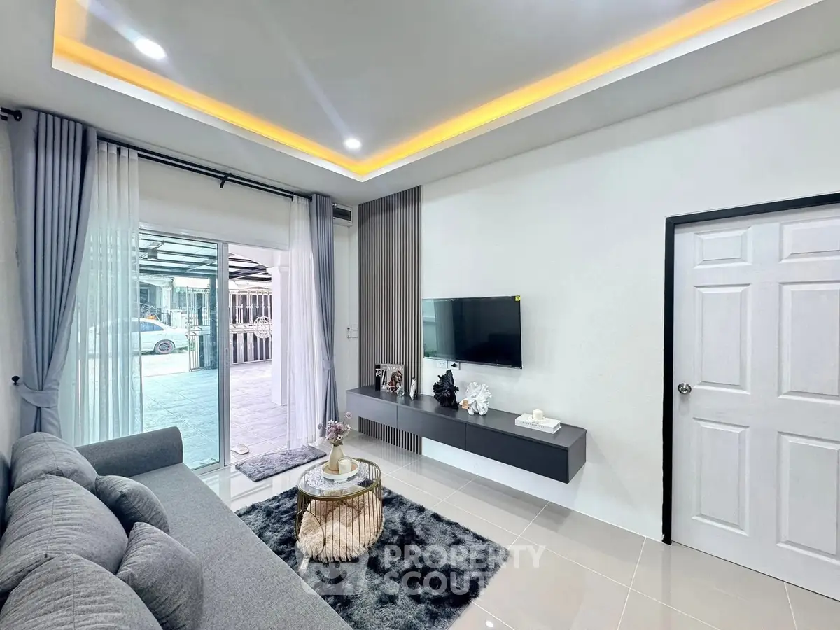 Modern living room with sleek decor and large window opening to outdoor view.