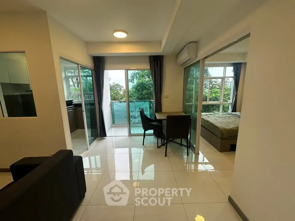 Modern apartment with open layout, featuring a cozy living area, dining space, and a balcony with lush views.