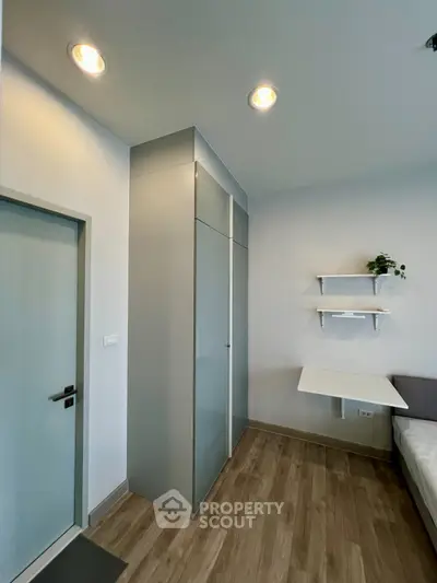 Modern bedroom with sleek wardrobe and foldable desk, perfect for compact living spaces.